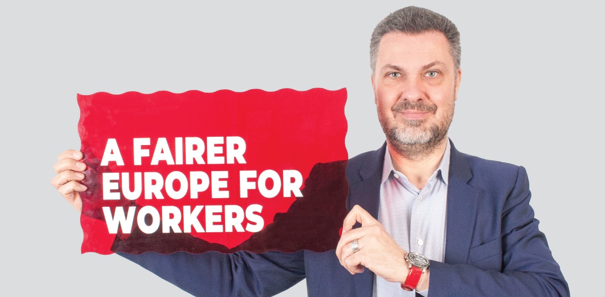 ETUC General Secretary Luca Visentini holds a sign saying: "A fairer Europe for workers"