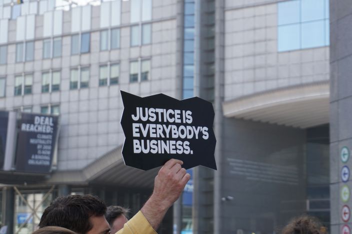 Someone holding up a sign reading 'Justice is everybody's business'